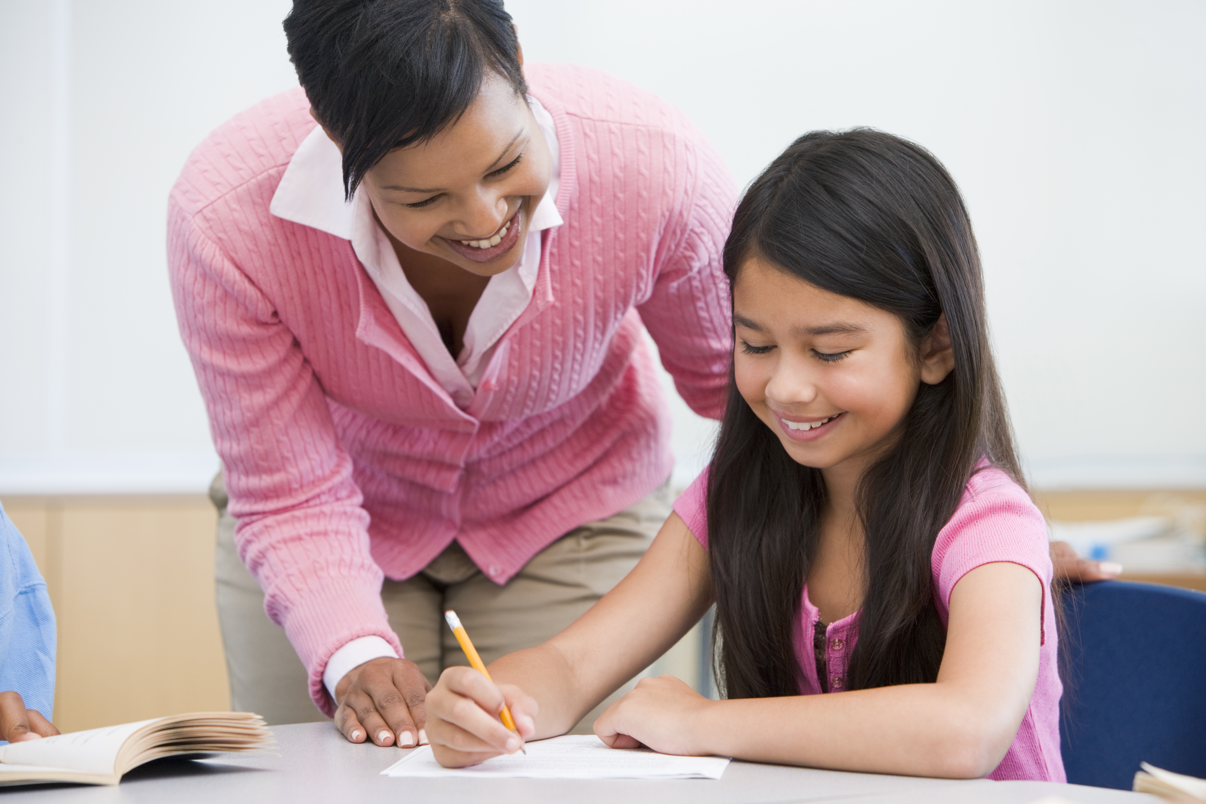 Teacher with student at desk.